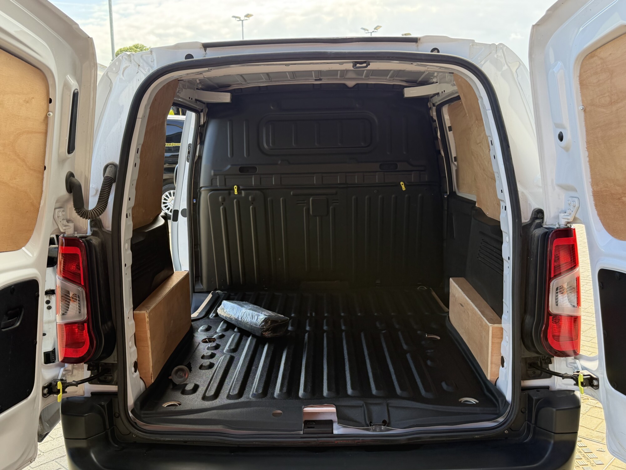 White Peugeot Partner van load area with rear doors open and plywood lining